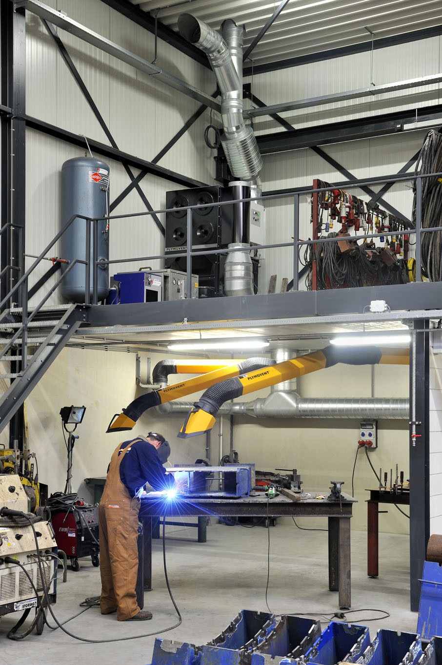 Welder working beneath yellow Plymovent fume extraction arms